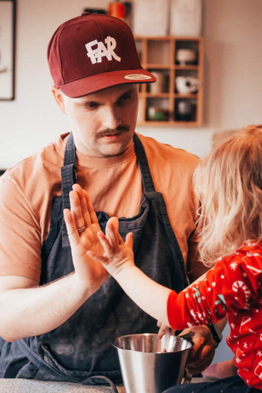 Nørdefar og datter giver high-five over decilitermål med pizzasovs